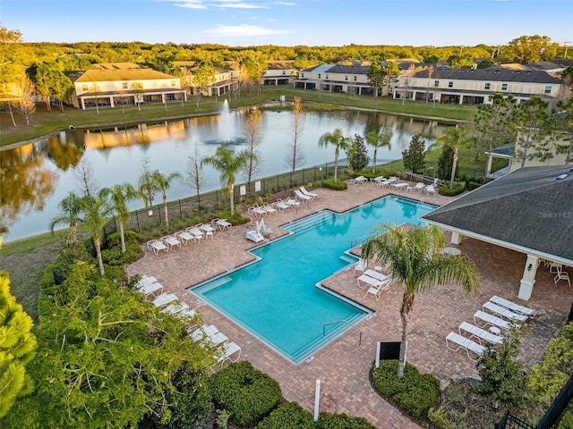 community pool featuring a residential view, a water view, a patio, and fence