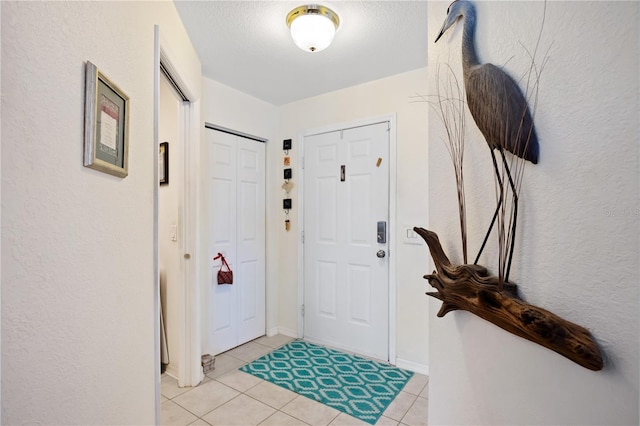 foyer entrance with light tile patterned flooring and a textured ceiling