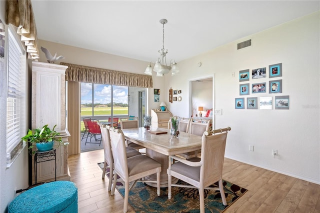 dining room with light wood finished floors, visible vents, baseboards, and a notable chandelier