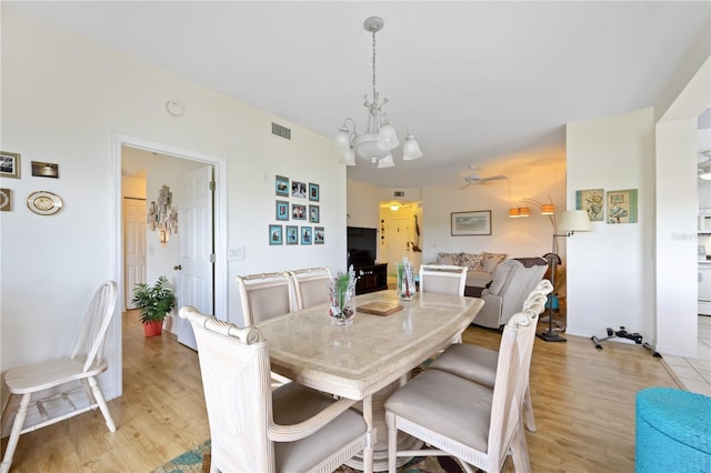 dining room featuring a notable chandelier, light wood-style floors, and visible vents