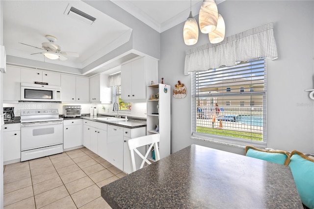 kitchen featuring dark countertops, visible vents, crown molding, white appliances, and a sink