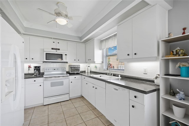 kitchen with white appliances, open shelves, a tray ceiling, a sink, and dark countertops