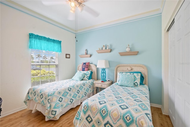 bedroom featuring crown molding, ceiling fan, baseboards, wood finished floors, and a closet