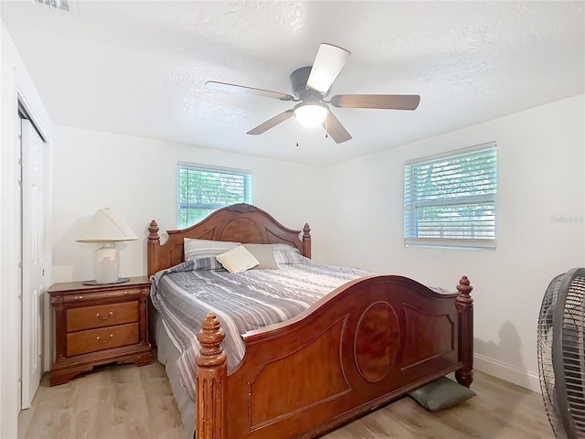 bedroom featuring a ceiling fan, light wood-type flooring, a closet, and a textured ceiling