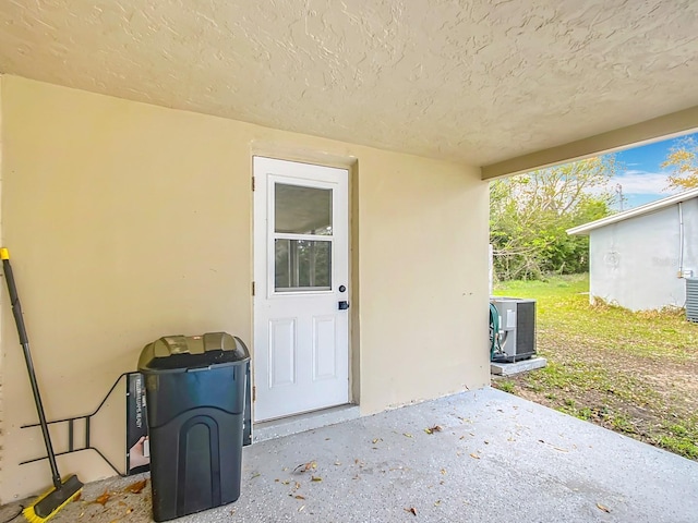 entrance to property with cooling unit, a patio area, and stucco siding