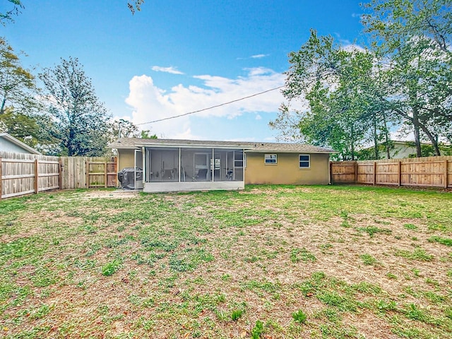 rear view of house with a yard, a fenced backyard, and a sunroom