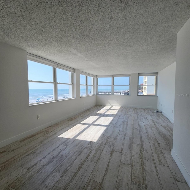 spare room featuring a wealth of natural light, a textured ceiling, and wood finished floors