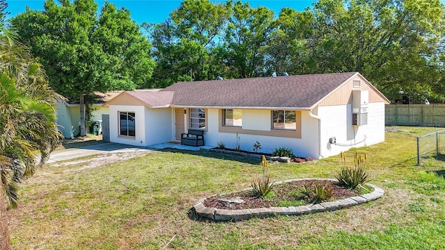 view of front of property with stucco siding, roof with shingles, a front yard, and fence