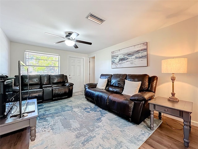 living room with ceiling fan, visible vents, and wood finished floors