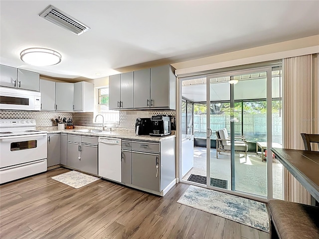 kitchen with visible vents, gray cabinets, white appliances, and a sink