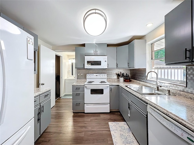 kitchen with a sink, decorative backsplash, white appliances, and gray cabinets