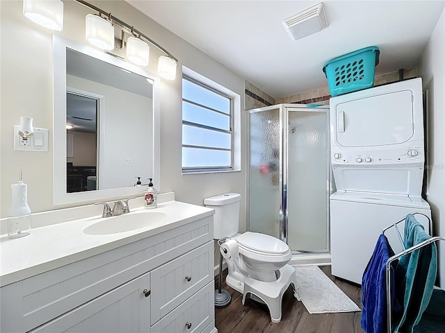 bathroom featuring vanity, wood finished floors, visible vents, stacked washing maching and dryer, and a shower stall