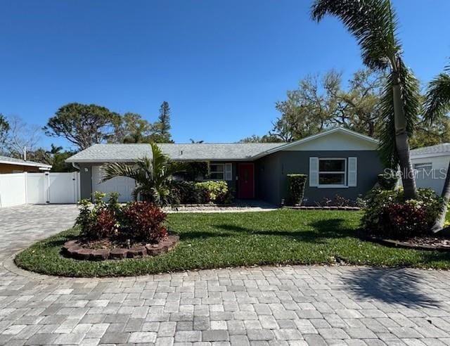 single story home with a garage, decorative driveway, a front lawn, and fence