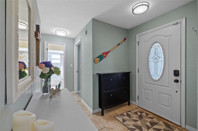 entrance foyer with light tile patterned flooring, a textured ceiling, and baseboards