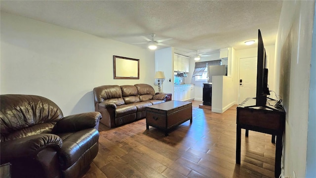 living room with ceiling fan, wood finished floors, and a textured ceiling