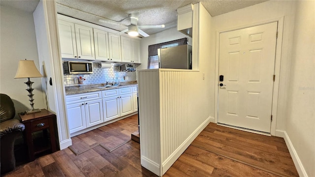 kitchen with ceiling fan, stainless steel microwave, dark wood finished floors, and white cabinetry