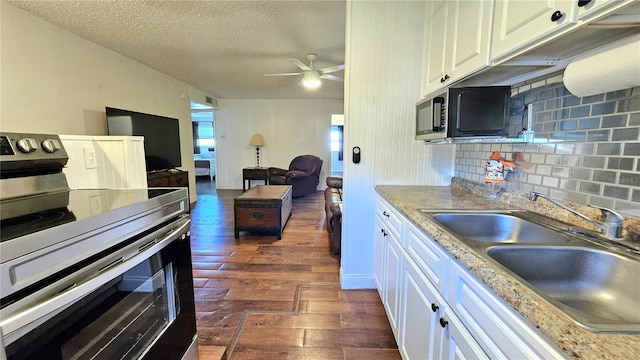 kitchen featuring tasteful backsplash, dark wood-type flooring, stainless steel electric stove, white cabinetry, and a sink