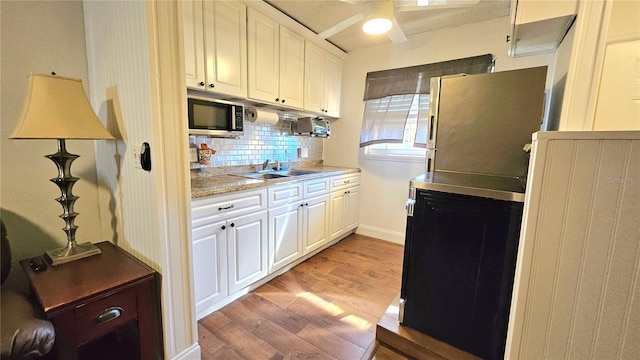 kitchen with light countertops, decorative backsplash, light wood-style flooring, appliances with stainless steel finishes, and a sink