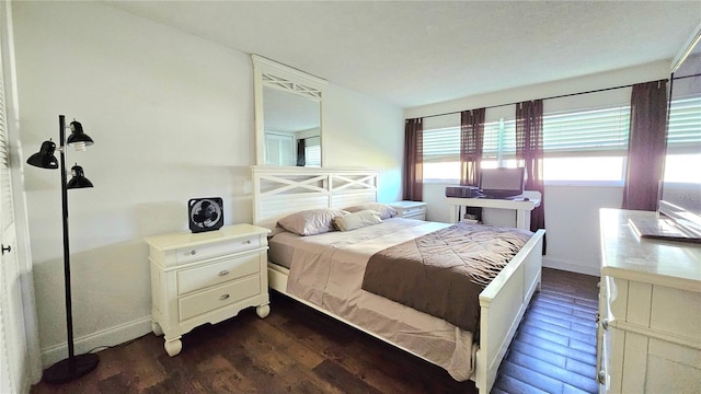 bedroom with baseboards and dark wood-type flooring