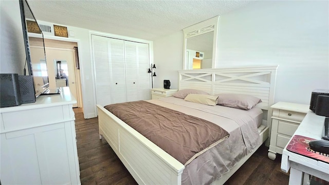 bedroom featuring dark wood-style floors, visible vents, a textured ceiling, and a closet