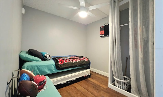 bedroom featuring ceiling fan, baseboards, and wood finished floors