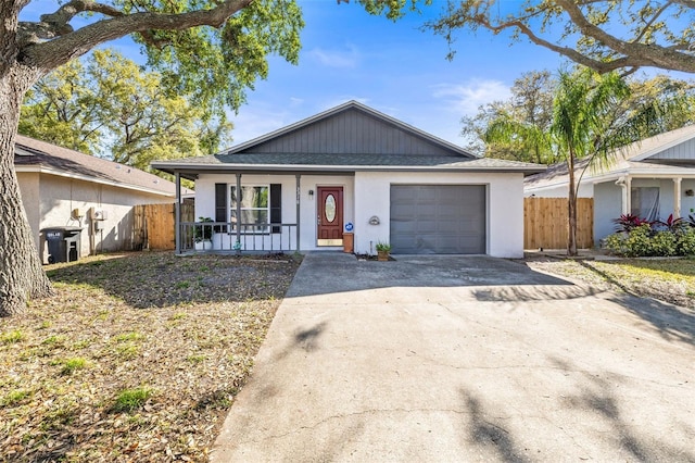 view of front of property with fence, an attached garage, covered porch, stucco siding, and concrete driveway