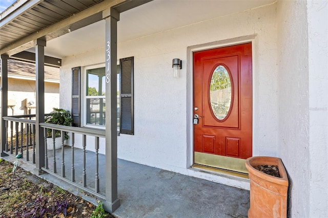 entrance to property featuring stucco siding and covered porch