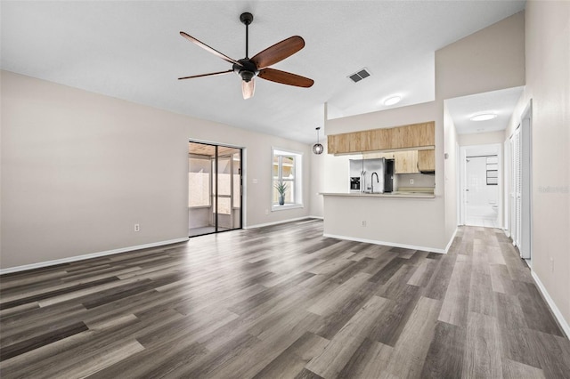 unfurnished living room featuring dark wood finished floors, visible vents, baseboards, and ceiling fan