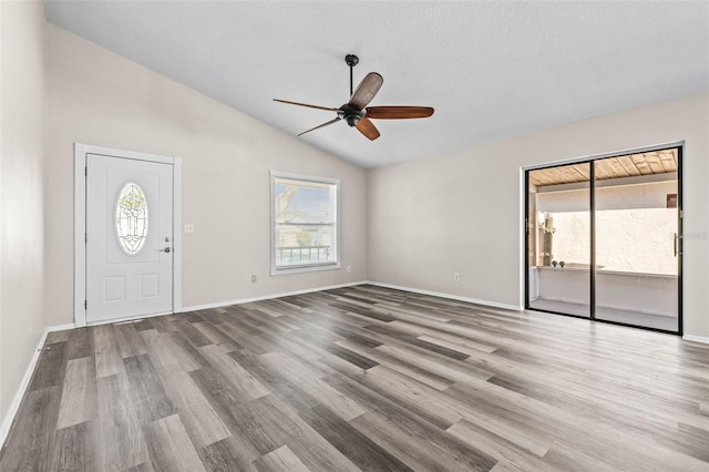 entrance foyer with vaulted ceiling, wood finished floors, a ceiling fan, and baseboards