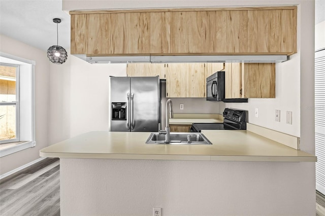 kitchen featuring black appliances, light brown cabinets, a peninsula, and a sink