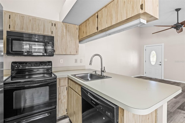 kitchen with a sink, black appliances, a peninsula, and light brown cabinetry