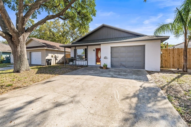 ranch-style home with stucco siding, fence, covered porch, concrete driveway, and a garage