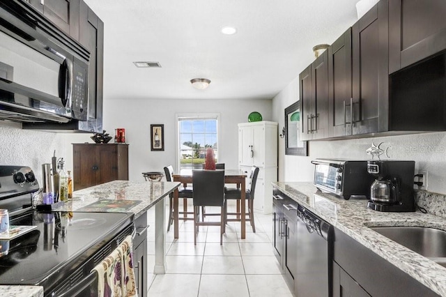 kitchen featuring visible vents, range with electric cooktop, black microwave, dishwasher, and light tile patterned flooring