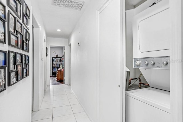 washroom featuring baseboards, visible vents, stacked washing maching and dryer, laundry area, and light tile patterned flooring