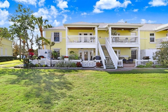 rear view of property with fence, stairs, a lawn, stucco siding, and a patio