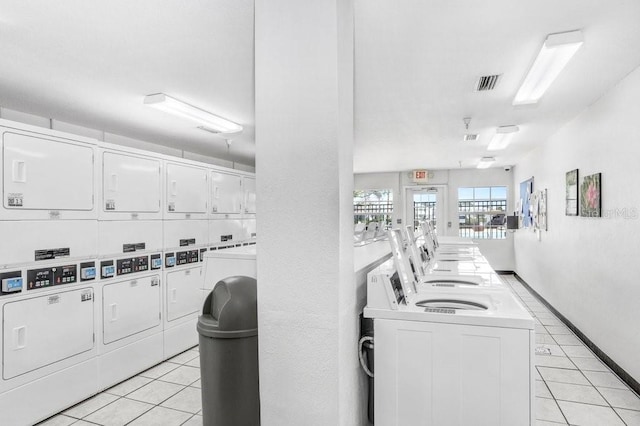 common laundry area with light tile patterned floors, visible vents, stacked washing maching and dryer, and baseboards