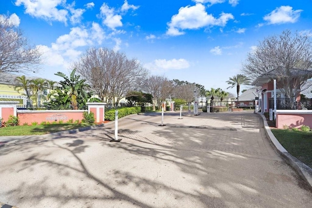 view of street with curbs, a gated entry, and a gate