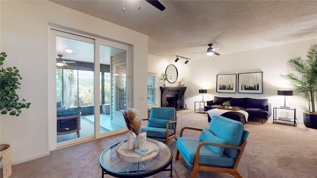 living room featuring carpet, ceiling fan, a fireplace, rail lighting, and a textured ceiling