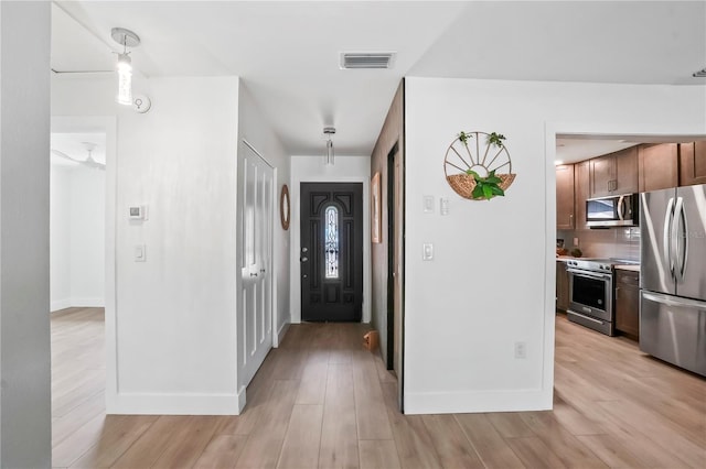 foyer with light wood-type flooring, visible vents, and baseboards