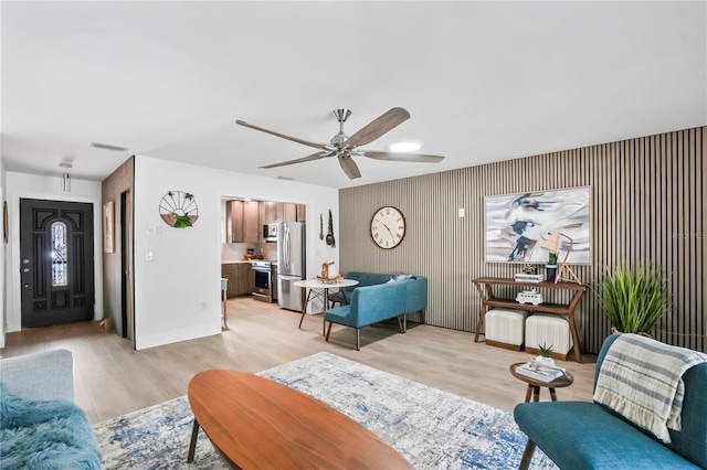 living room with visible vents, baseboards, light wood-style floors, and a ceiling fan