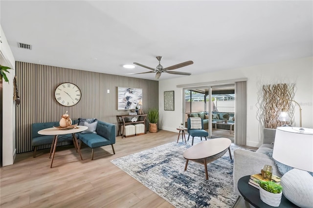 living room featuring ceiling fan, visible vents, baseboards, and light wood-style flooring