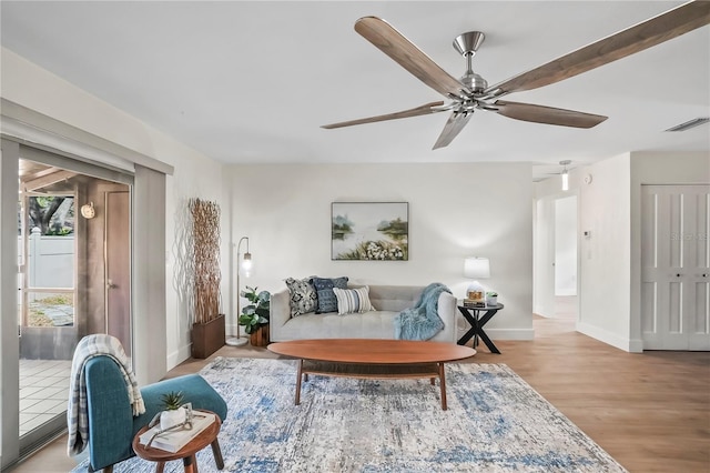 living room with visible vents, baseboards, ceiling fan, and wood finished floors