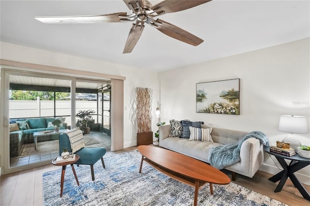 living area featuring baseboards, ceiling fan, and wood finished floors