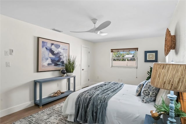 bedroom featuring a ceiling fan, wood finished floors, visible vents, and baseboards