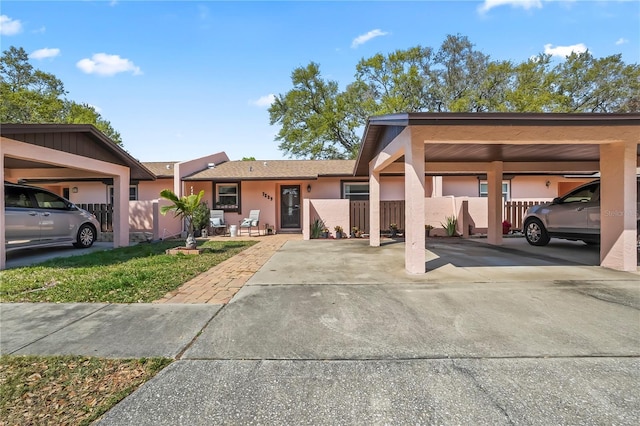 view of front of house with covered parking, fence, and stucco siding