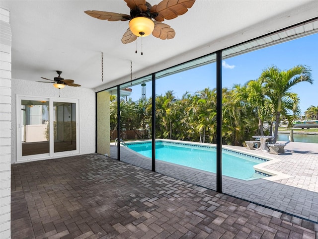 pool with glass enclosure, ceiling fan, and a patio area