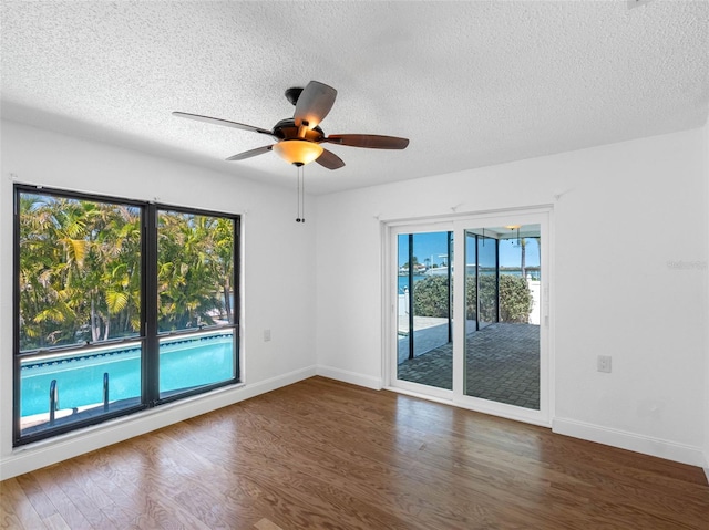 unfurnished room featuring a textured ceiling, baseboards, ceiling fan, and wood finished floors