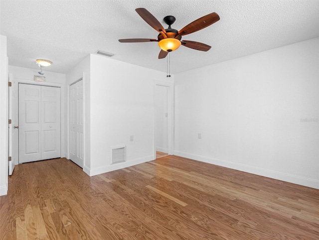 unfurnished room featuring visible vents, a textured ceiling, ceiling fan, and wood finished floors