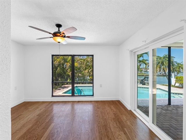 unfurnished room featuring ceiling fan, baseboards, a textured ceiling, and wood finished floors