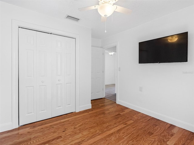 unfurnished bedroom with baseboards, visible vents, light wood finished floors, ceiling fan, and a closet